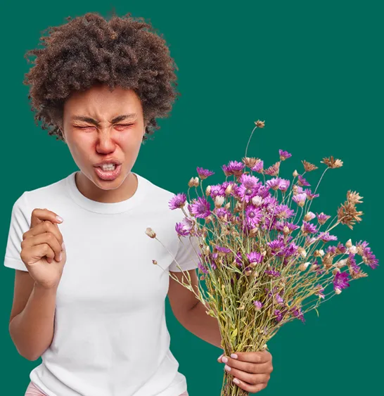 Une personne tient un bouquet de fleurs dans ses mains et grimace, comme si elle avait envie d’éternuer.