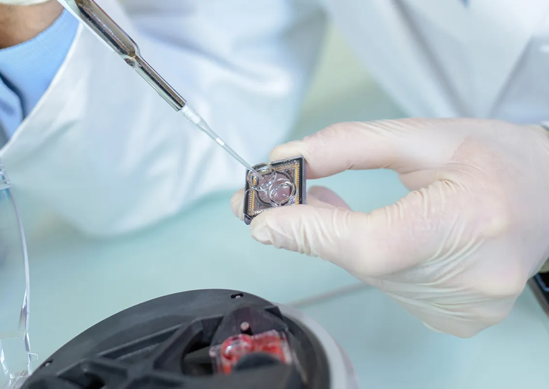 Une personne utilise une pipette pour manipuler un échantillon dans un laboratoire.