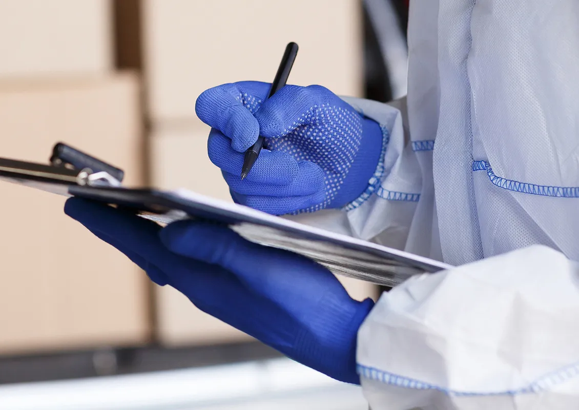 Une personne note des éléments sur une feuille placée sur une planchette à pince.