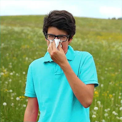 Une personne est dans un champ et se mouche.