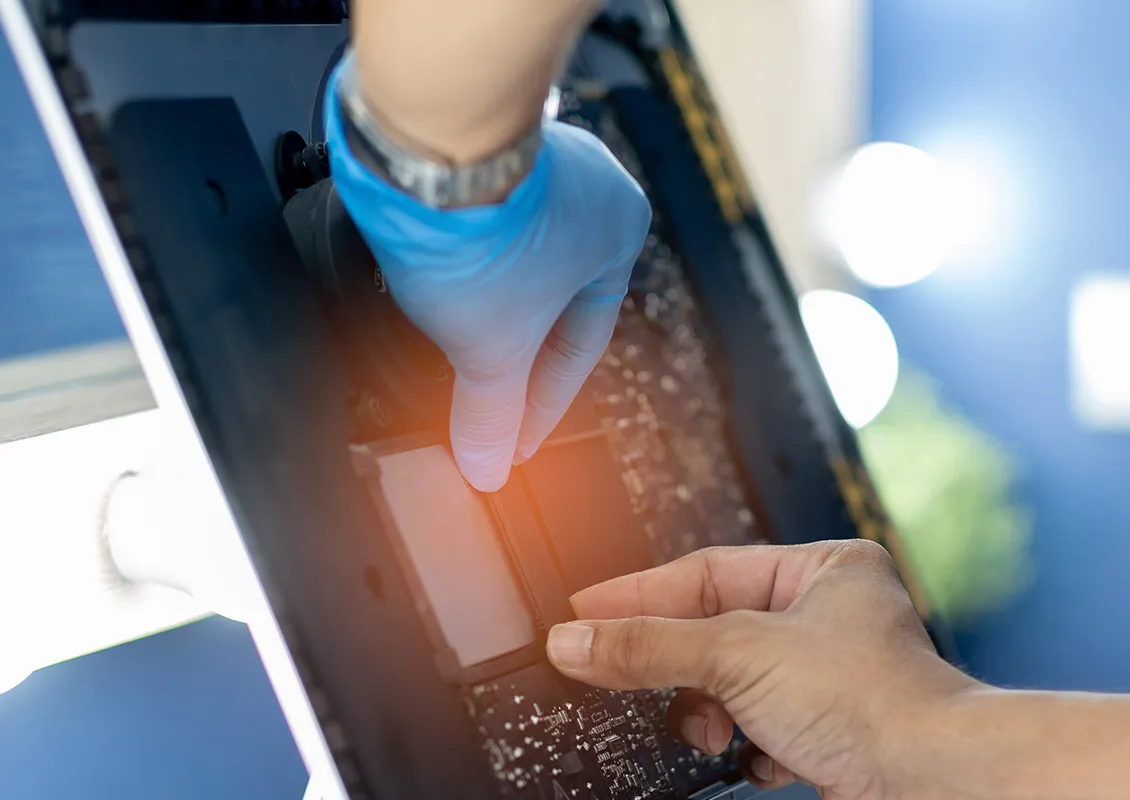 Une personne portant des gants répare ou assemble un appareil électronique.
